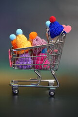 miniature chrome supermarket trolley full of yarn hats