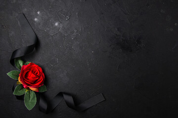 top view black bow with red flower on dark surface funeral death