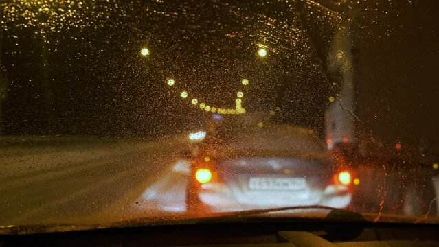 Traffic jams concept at night. From inside the car. Drops on the windshield. Selective focus
