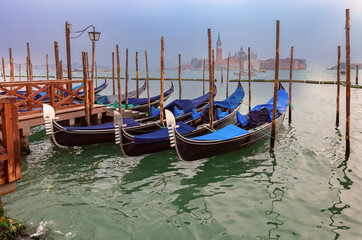 Fototapeta na wymiar Traditional gondolas at the pier with the island of San Maggiore in the background.