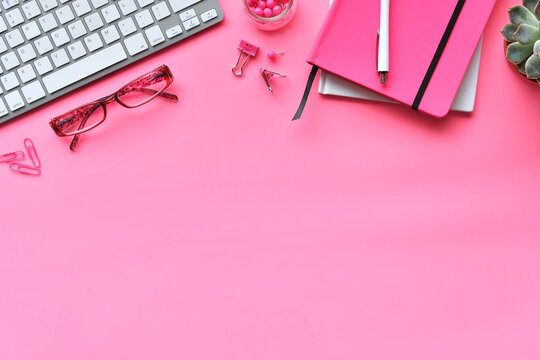 Pink desktop with keyboard notebook colorful pink office school supplies flat lay  background