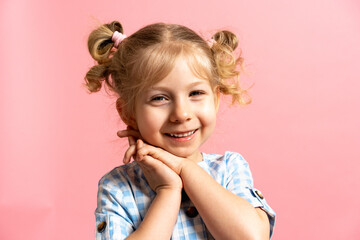 a little blonde girl on a pink isolated background with a cute smile