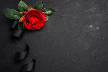 top view of black bow with red flower on a dark background funeral death