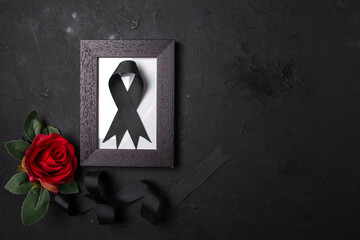 top view of picture frame with black bow and flower on dark surface death funeral