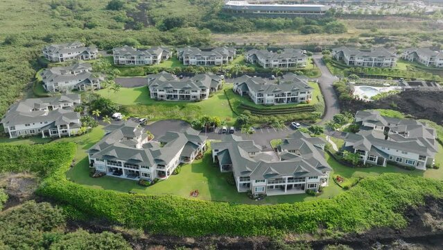 Expensive real estate island homes on Hawaii. Cinematic aerial of volcanic Big Island landscape with black lava rocks covered by bright fresh greenery and expensive large island Villas mansion houses