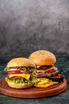 Delicious sandwiches fries ketchup on wooden board on dark mix color background