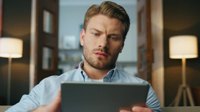 Focused man reading pad computer zoom out. Serious businessman zooming screen