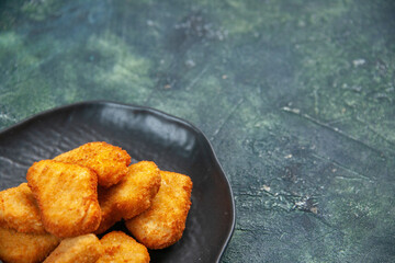 Close up shot of tasty chicken nuggets in black plate on dark background with free space