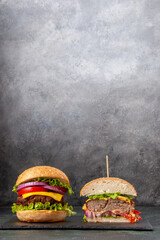 Close up view of cut whole tasty sandwiches on black tray on dark mix color background
