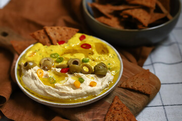Dip hummus with olives and nachos chips