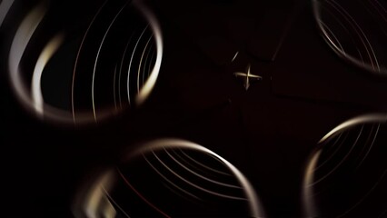 Movie tape, graphics composition detail element. Reel tape spool rolling in a dark classic cinema concept. CG close up vertical trucking shot, ideal for movie show intros, logos or transitions