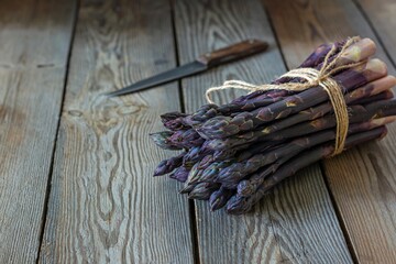 Fresh bunch of purple asparagus on dark wooden background. Healthy food concept. The vegetable is rich in fiber, a natural prebiotic.