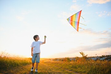 Children launch a kite in the field at sunset.