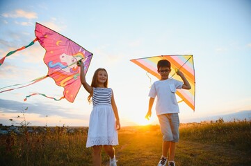 Children launch a kite in the field at sunset