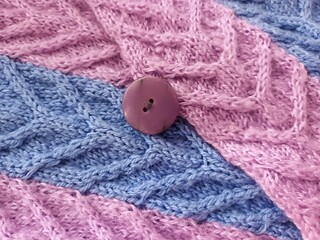 Button on a knitted background of blue and purple colors