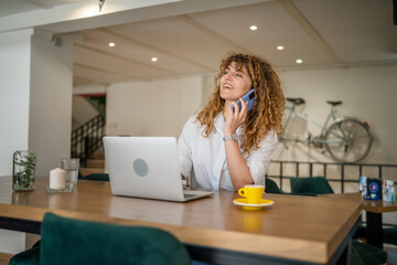 Obraz premium Woman use smartphone make a call talk while work on laptop from cafe