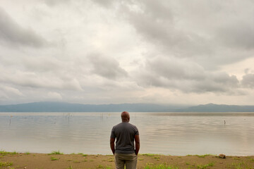 African American man tourist looking out over the still waters of Lake Bosumtwi, Ghana