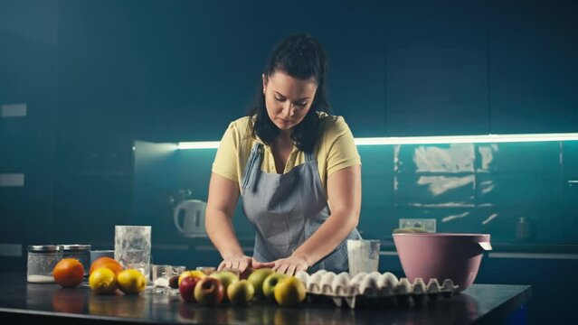 Caucasian woman rolling out dough in the kitchen. The chef prepares a pastry for making cakes. Sweets prepared at home. High quality 4k footage