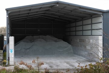 Salt storage shed with a large pile of salt. - obrazy, fototapety, plakaty