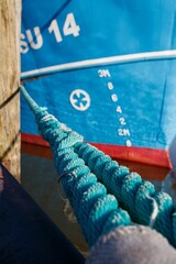 Small sailboat is secured to a dock with bright blue ropes, Husum