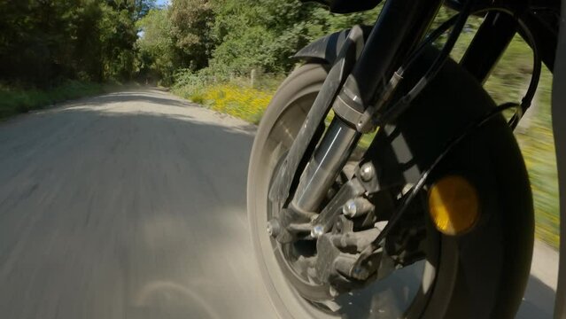Front suspension with spoked wheel of a motorcycle riding on a gravel road in forest adventure