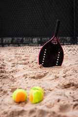 Female Beach Tennis racket on the sand with balls. Women's Beach Tennis. Copy Space - Vertical photo