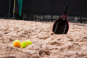 Female Beach Tennis racket on the sand with balls. Women's Beach Tennis. Copy Space - Horizontal photo