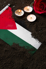 front view of palestinian flag with burning candles and flower on a dark soil death palestine