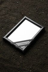 front view of picture frame on dark soil grim reaper death photo funeral portrait