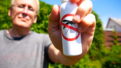 Close-up of anti mosquito spray in the hand of an elderly man staying outdoors