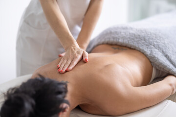 Obraz na płótnie Canvas Detail of a masseuse providing a massage to a female client on her sholder blade