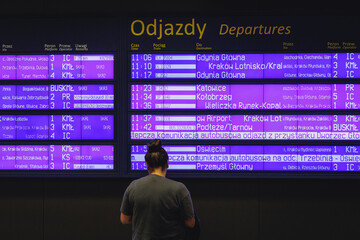Passenger in front of timetable on railway station in Krakow, Poland