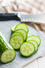 Sliced fresh green cucumber on cutting board.