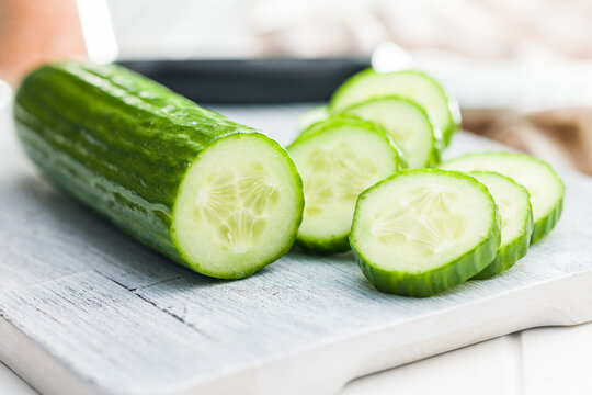 Sliced fresh green cucumber on cutting board.