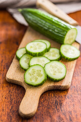 Sliced fresh green cucumber on cutting board.