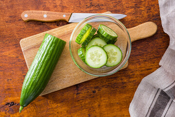 Sliced fresh green cucumber in bowl. Top view.