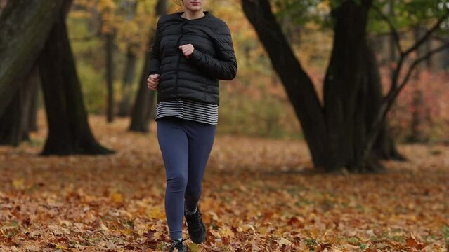 sports girl runs in the park. Sports, running. Autumn, forest.