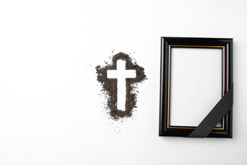 top view of cross shape with picture frame on white surface soil funeral grim reaper