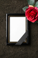 top view of picture frame with red flower on a dark soil grim reaper funeral portrait death
