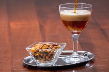 Glass of Belgian abbey brown beer with snack nuts in bar