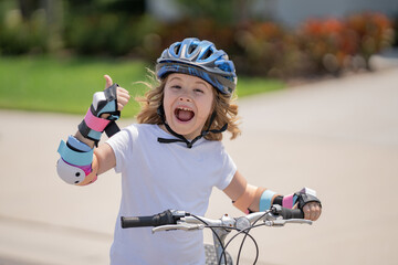 Naklejka premium Little kid boy riding a bike in summer park. Children learning to drive a bicycle on a driveway outside. Kid riding bikes in the city wearing helmets as protective gear. Child on bicycle outdoor.
