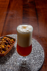 Glass of Belgian light blond beer made in abbey and bowl with party mix nuts