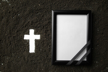 top view of white cross shape with dark soil and picture frame death grim reaper funeral