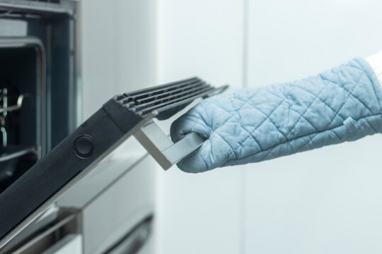 Homemade Cooking: Kitchen Glove-Protected Hand Opens the Oven Door