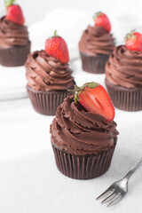 Chocolate cupcake with dark chocolate buttercream and strawberries, double chocolate cupcakes with american buttercream, tall swirl frosting on a cupcake with a strawberry