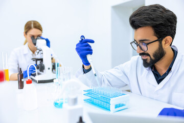 Fototapeta premium Team of scientists examining sample, using microscope and chemical liquids in flask in modern lab
