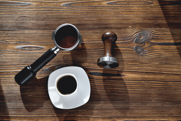 a cup of coffee, a coffee horn and a tamper on a wooden background, selective focus