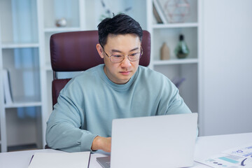 Businessman using laptop computer in office. Asian man, entrepreneur, small business owner working online.