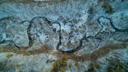 An aerial drone shot of a creek running through a forest during a winter sunrise