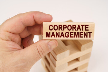 A man holds in his hands a wooden block with the inscription - Corporate Management